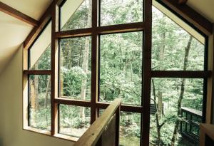 a window in a cabin looking out at the forest at Karuizawa Forest Seasons Villa in Karuizawa