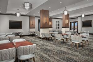 Embassy Suites Springfield في سبرينغفيلد: غرفة طعام مع طاولات وكراسي وتلفزيون