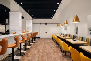 DoubleTree by Hilton Norfolk Airport في نورفولك: غرفة طعام بطاولات خشبية وكراسي صفراء
