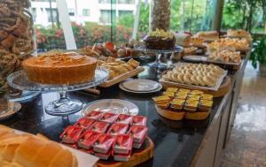 un buffet lleno de diferentes tipos de pasteles y tartas en Flat Marulhos Resort Porto de Galinhas en Porto De Galinhas