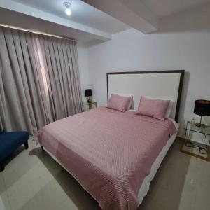 a bedroom with a large bed with pink pillows at Lujoso PH en DT, área de trabajo y Gym, 1BR in Santo Domingo