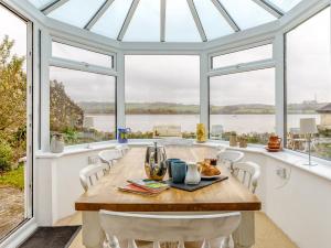 a dining room with a table and chairs and windows at 4 Bed in Bere Alston RTIDE in Tamerton Foliot