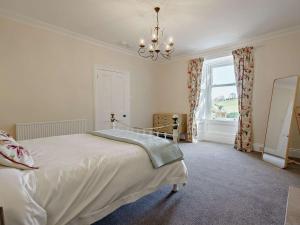 a bedroom with a bed with a chandelier and a window at 3 Bed in Biggar 82924 in Biggar