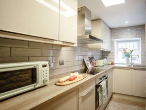 a kitchen with a microwave and a cutting board at 2 Bed in Rothbury 82238 in Rothbury
