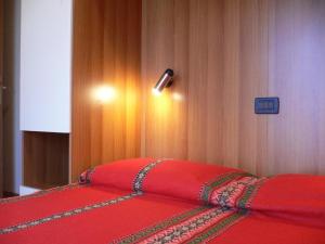 - une chambre avec un lit rouge et une lumière sur le mur dans l'établissement Große Wohnung in Rosolina Mare mit Grill und Garten, à Rosolina Mare