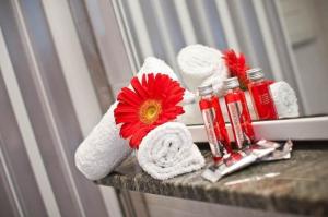 La salle de bains est pourvue de serviettes et d'une fleur rouge sur un comptoir. dans l'établissement Große Wohnung in Rosolina Mare mit Grill und Garten, à Rosolina Mare