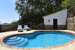 ein Pool mit zwei Stühlen und ein Gebäude in der Unterkunft Ferienhaus mit Privatpool für 4 Personen ca 120 m in Competa, Andalusien Costa del Sol in Cómpeta