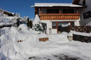 a house covered in snow in front of a house at Schönes Ferienhaus in Lechbruck Am See mit Großer Terrasse und Bergblick in Lechbruck
