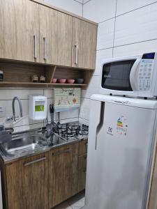 a kitchen with a microwave on top of a refrigerator at Consulado Americano apartamento 50 metros da entrada para Visto Consulado EUA Porto Alegre com garagem in Porto Alegre