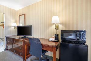 a hotel room with a desk with a television and a microwave at Quality Inn Vienna - Tysons Corner in Tysons Corner