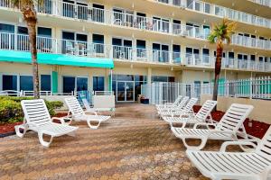 a row of white lounge chairs in front of a hotel at Harbour Beach Resort Unit 808 in Daytona Beach