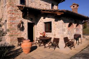 een stenen huis met een tafel en stoelen buiten bij Ferienwohnung in einem toskanischen Landhaus, mit privater Panoramaterrasse in Poppi