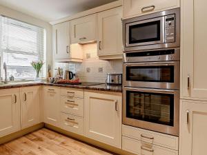 a kitchen with white cabinets and stainless steel appliances at 3 Bed in Tenby FB053 in Tenby