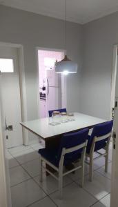 a kitchen with a white table and blue chairs at Pé na Areia em Santos in Santos