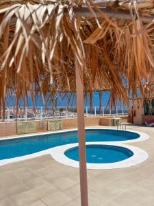 a large swimming pool with a straw roof at Paz Ocean View, Air condition, Wifi, Heated pool in San Miguel de Abona
