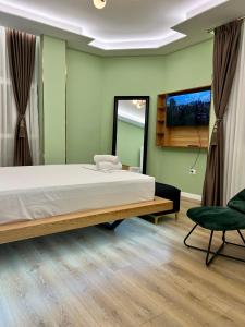 um quarto com uma cama grande e uma cadeira em Spiranca Apartments & Rooms em Tirana