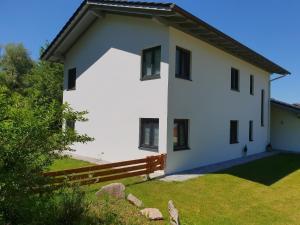 a white house with a wooden fence in front of it at Ferienwohnung Casa Bianka in Fridolfing in Fridolfing