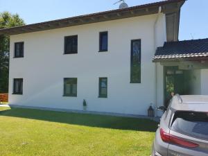 a white house with a car parked in front of it at Ferienwohnung Casa Bianka in Fridolfing in Fridolfing