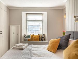 ein Schlafzimmer mit einem Bett mit gelben Kissen und einem Fenster in der Unterkunft 1 Bed in Wadebridge 87740 in Wadebridge