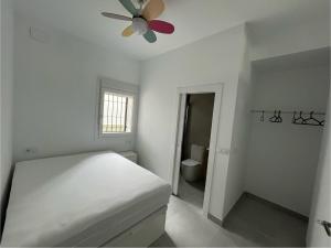 a white bedroom with a bed and a ceiling fan at Baeza aloja in Baeza