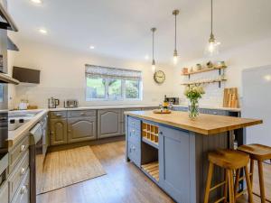 a kitchen with a blue island with a wooden counter top at 3 Bed in Llanrhaeadr Ym Mochnant 85799 in Llanrhaeadr-ym-Mochnant
