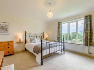 3 Bed in Llanrhaeadr Ym Mochnant 85799 في Llanrhaeadr-ym-Mochnant: غرفة نوم بسرير ونافذة كبيرة
