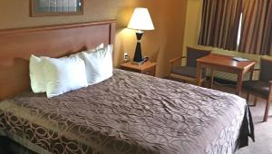 a hotel room with a bed with a desk and a desk at Xecutive Inn and Suites in Center