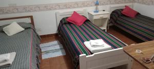 a room with two beds and a table and a table at Residencial Sissus in San Carlos de Bariloche
