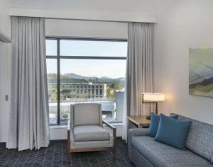 a living room with a couch and a chair and a window at Embassy Suites By Hilton Asheville Downtown in Asheville