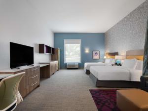 a hotel room with two beds and a flat screen tv at Home2 Suites By Hilton Round Rock Medical Center in Round Rock