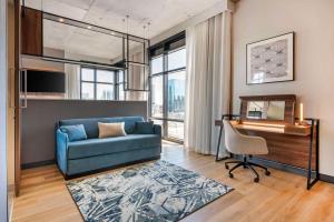 a living room with a blue couch and a piano at Cambria Hotel Nashville Midtown in Nashville