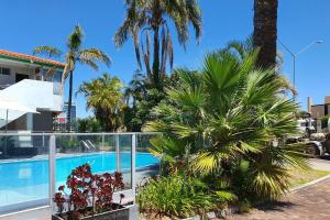 a resort with a swimming pool and palm trees at Econo Lodge Rivervale in Perth