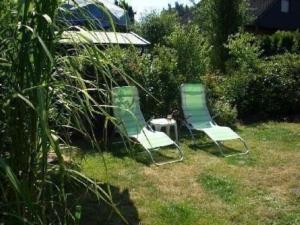 dos sillas verdes y una mesa en un patio en Gemütlicher Ferienbungalow mit Garten im ruhigen Naturgebiet en Hechthausen