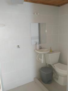 a white bathroom with a toilet and a sink at Hostal El Balcon de madera in Norcasia