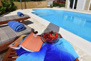 un bol de fruta en una mesa junto a la piscina en Strandnahes, ruhig gelegenes Ferienhaus mit eigenem Pool auf der Insel Murter, en Murter