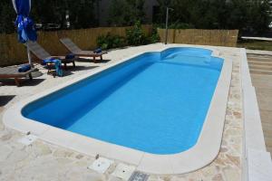 una gran piscina azul con 2 sillas junto a ella en Strandnahes, ruhig gelegenes Ferienhaus mit eigenem Pool auf der Insel Murter, en Murter