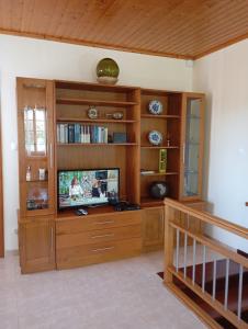 una sala de estar con TV en un centro de entretenimiento de madera en Adega Pedra do Lagar en Calheta de Nesquim