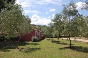 una fila di alberi di fronte a un edificio rosso di Gästezimmer für 3 Personen 1 Kind ca 30 qm in Loiri Porto San Paolo, Sardinien Gallura a Biacci