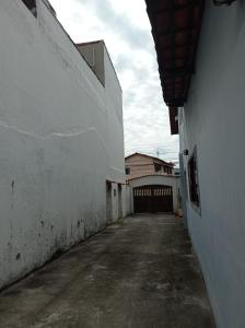 Une allée vide avec un bâtiment blanc et une clôture dans l'établissement Casa Aconchegante., à Cabo Frio