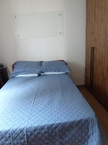 - un lit avec une couette bleue dans une chambre dans l'établissement Casa Aconchegante., à Cabo Frio