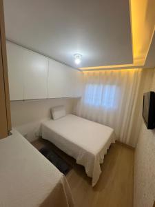 a small room with two beds and a window at Apartamento Moderno em Caxias do Sul in Caxias do Sul