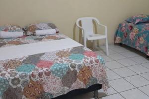 1 Schlafzimmer mit 2 Betten und einem weißen Stuhl in der Unterkunft Casa DOM Santo Amaro do Maranhão in Santo Amaro