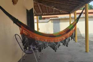 eine Hängematte auf einer Terrasse mit Stühlen unter dem Dach in der Unterkunft Casa DOM Santo Amaro do Maranhão in Santo Amaro
