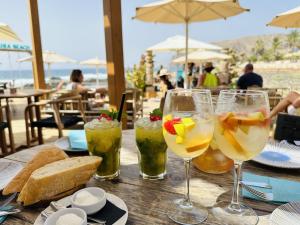 a wooden table with three glasses of drinks on a table at PalmMar Balandros Deluxe By Deihu Experiences in Palm-mar