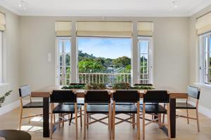 une salle à manger avec une table, des chaises et une grande fenêtre dans l'établissement Grande Vista 5Br Manor with Pool & Mt Eden Views, à Auckland