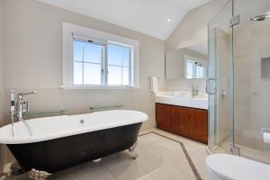 a bathroom with a tub and a sink and a toilet at Grande Vista 5Br Manor with Pool & Mt Eden Views in Auckland