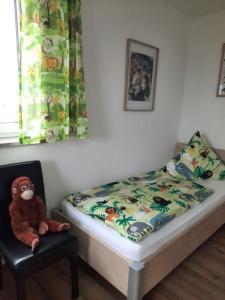 un lit avec un singe farci assis dans une chaise dans l'établissement Ferienwohnung 2 Schlafzimmer Nähe Legoland Günzburg mit Balkon und herrlichem Fernblick, à Burtenbach