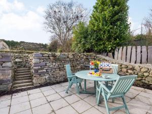 una mesa y sillas en un patio con una pared de piedra en 2 Bed in Bethesda 86740, en Llanddeiniolen