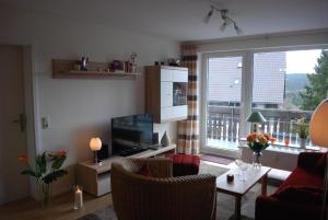sala de estar con TV y mesa con sillas en Ferienwohnung mit Balkon in Hohegeiß, en Braunlage