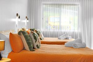 two beds in a bedroom with orange sheets and pillows at 14 Scenic Studio in Geelong